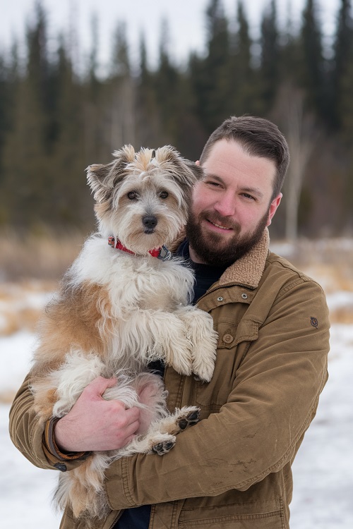 un chien dans les bras de son maître illustrant les relations entre chiens et humains.